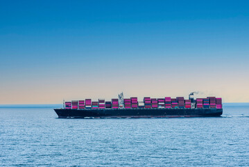 Large, fully loaded, cargo container ship sailing through calm, blue Indian Ocean. International...
