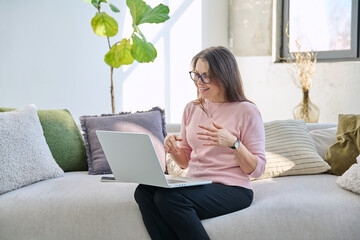 Middle aged woman working remotely, video conference, using laptop