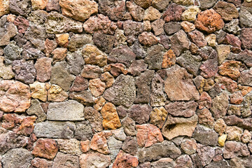 colored unprocessed rocky stones of natural origin, a wall of stones in concrete, background for walls and wallpapers