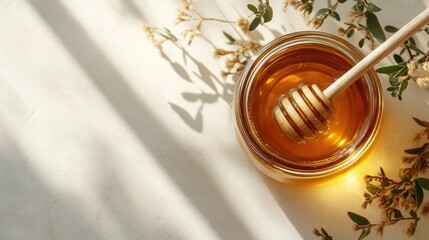 Fototapeta premium A glass jar of honey with a wooden honey dipper, on a white background