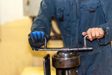 Engine room crew member standing over a repaired engine part on a cargo ship. The motorman is...