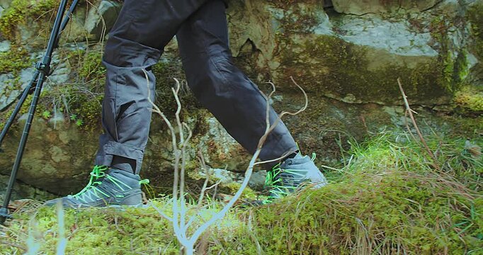 Close-Up of Legs in Mountain Boots Walking Through the Forest. The hiker steps confidently along a trail surrounded by nature and fallen leaves.