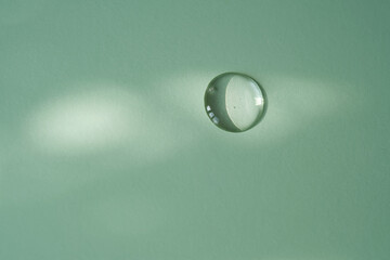 A drop of micellar water on a green background.