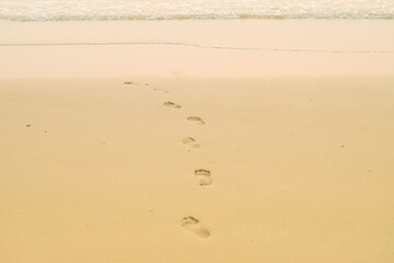 Footprints of human feet on the sand near the water on the beach.