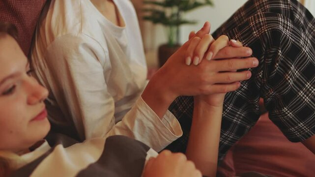 Teenage siblings sitting closely on bed, holding hands with deep emotional connection, sharing tender moment of familial support and trust in comfortable home environment