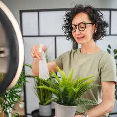 Mature woman have live stream on mobile phone about home plant care