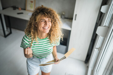 caucasian woman open mail letter or document envelope at home