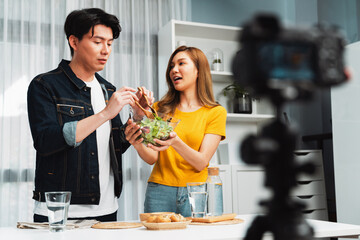 Cooking show live streaming with two chef influencers making mixed salad, all ingredients with dressing with good taste for easy special menu served with bun bread on table record by camera. Infobahn.