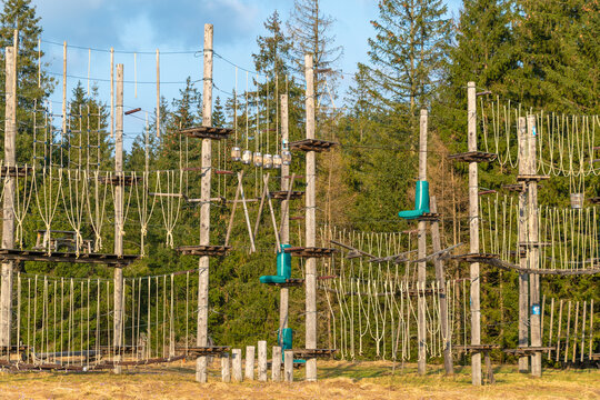 A ropes course stands in a clearing, surrounded by forest. outdoor adventure challenges for climbing and balance.