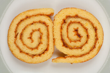 Two slices of Swiss roll with jam filling are placed next to each other on a plate