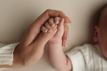 Close-up little hand of child and palm of mother and father. The newborn baby has a firm grip on the parent's finger after birth. A newborn holds on to mom's, dad's finger. 