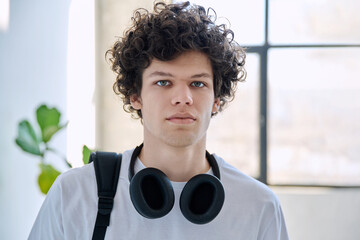 Headshot portrait handsome young man with headphones, backpack