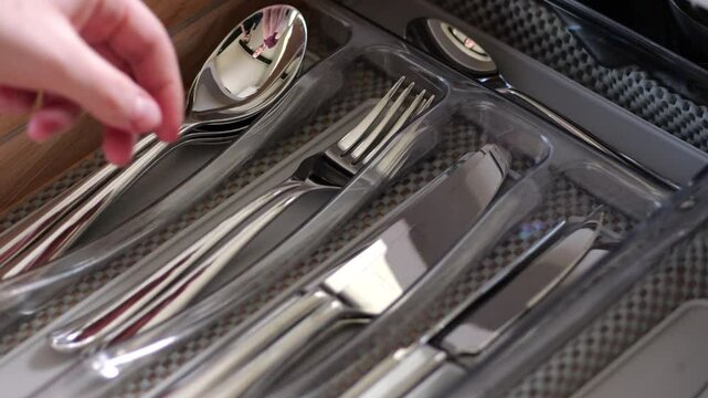 Person opening drawer, taking and placing cutlery in slow motion