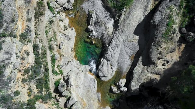Aerial drone view of a small waterfall on the Mula River, Murcia Region, Spain, with crystal-clear emerald waters.