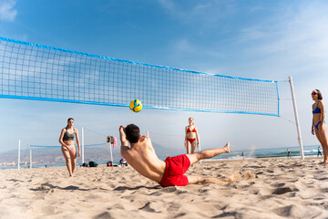 Friends playing beach volleyball under blue sky