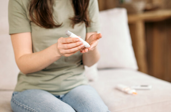 Woman using a glucometer to check blood sugar level at home close-up, concept of diabetes control and self-monitoring.