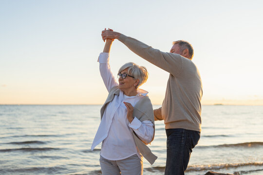 Keep moving. Romantic senior mature couple dancing together on beach outdoor recreation. Happy smiling family retired man woman husband wife having fun enjoying time together. Family moment love care