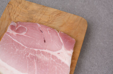 A piece of ham lying on a wooden board
