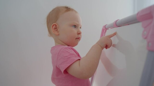 Toddler engages in creative play at a colorful easel in a bright and inviting room