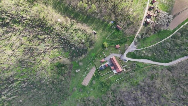 Aerial Top View of Rural Farmhouse with Red Roof Surrounded by Forest
