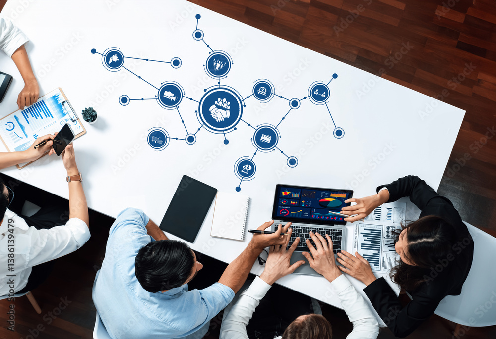 Fototapete A dynamic business team engages in brainstorming and analysis around a table, using technology and data visualizations to foster collaboration and innovative strategies. Amity