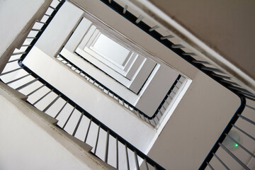 Staircase in an apartment building with metal railing seen upwards