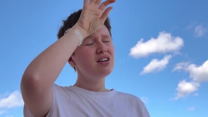 young beautiful woman suffering from heat against blue sky