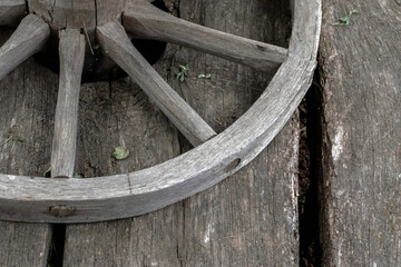 Fragment of a wooden wheel. A wooden wheel from an ancient cart lies on boards. View of a fragment of ancient technology for making a wheel from natural materials.