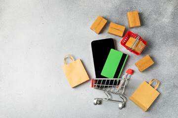 Online shopping concept.Cardboard box and shopping bags in a trolley on a bright colored...