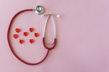 Stethoscope and red heart on pink background, top view. Space for text