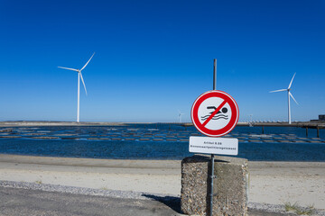 No swim sign on a wind farm in the Netherlands with wind turbines in the background