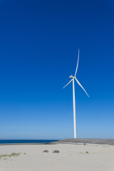 Wind turbine on the sand dunes with blue sky in the background