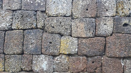 Old brick wall background, ancient castle stone wall in Thailand, fence made of large stones stacked in layers, ancient construction.