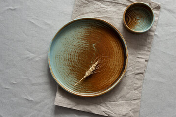 Round plate with a rim in a warm colors on a beige cotton tablecloth. Minimalistic composition with...