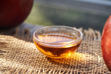 Apple cider vinegar in a glass bowl with red apples