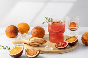 Refreshing cold drink of blood orange fruit in glass decorated fruit slice, thyme leaves on wooden...