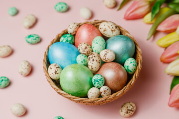 Easter eggsin basket on pink background with tulips.