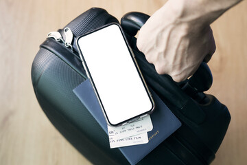 Man holding a suitcase with blank white mock up screen phone and air ticket at airport