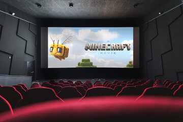 Fototapeta premium Minecraft movie theater screen displaying Minecraft Movie poster, viewed from empty red cinema seats.