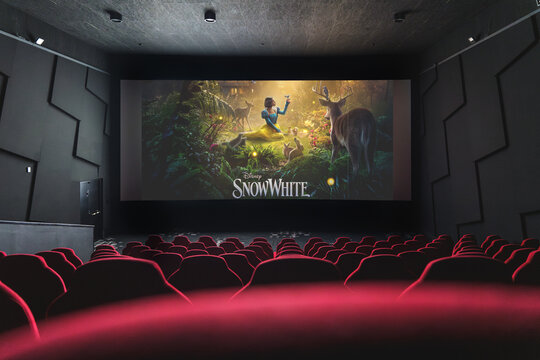 Movie theater screen displaying Disney Snow White film poster, viewed from empty red cinema seats.