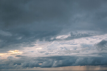 The sky is filled with clouds and the sun is shining through them. The clouds are white and fluffy,...