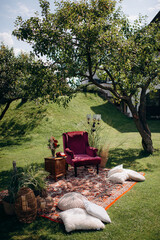 Cozy outdoor lounge with red velvet chair under a tree