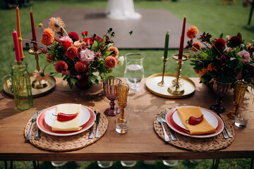 Rustic outdoor table setting with colorful flowers and chili peppers on plates