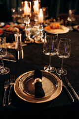 Elegant indoor table setting with gold and black by candlelight