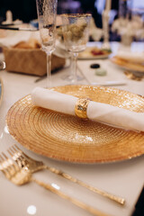 Elegant gold-themed table setting with textured plate, white napkin, and sparkling napkin ring