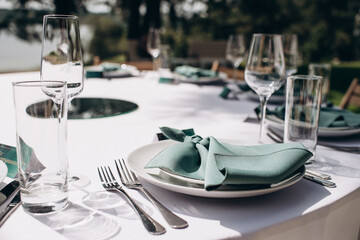 Elegant outdoor table setting with a knotted green napkin, white plates, and clear glassware