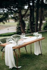 Elegant outdoor wedding presidium with a wooden table, white runner, and delicate floral accents