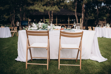 Elegant outdoor wedding presidium with a white tablecloth and simple floral arrangements on green grass