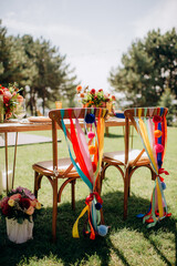 Festive outdoor wedding presidium with colorful ribbons, pom-poms, and floral arrangements