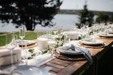 Fototapeta premium Elegant outdoor wedding table setting with a wooden table, white runner, white plates, and simple greenery garland